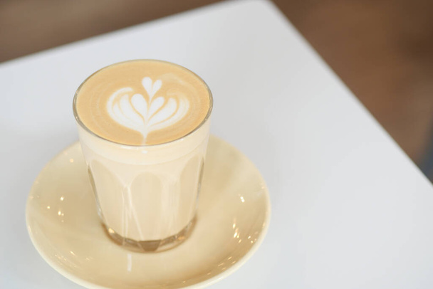 una taza de café tardío con diseño de forma de flor en la parte superior en la cafetería . - Foto, imagen