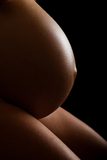 Nude pregnant woman belly on black background - Foto, Bild