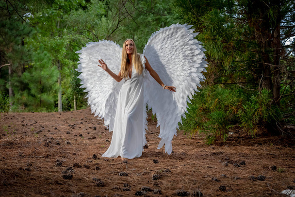 Великолепная блондинка модель позирует на открытом воздухе в то время как носить набор белых крыльев на Хэллоуин.  - Фото, изображение