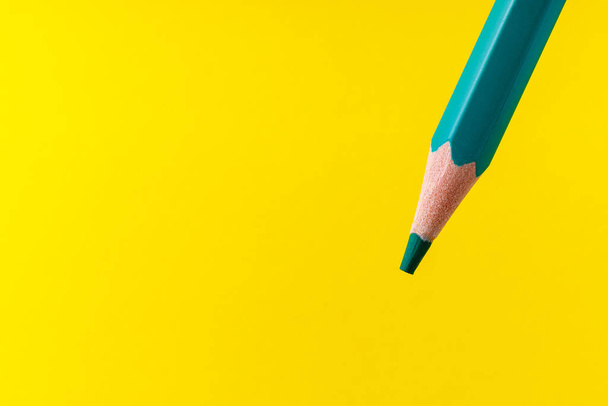 Colored pencil close-up with selective focus on the stylus and a blurred yellow background. Copy space for text. - Foto, Bild