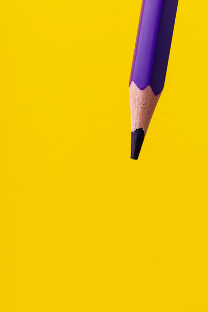 Colored pencil close-up with selective focus on the stylus and a blurred yellow background. Copy space for text. - Foto, afbeelding