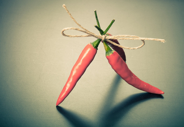 red hot chili peppers tied twine against dark background - Foto, Bild