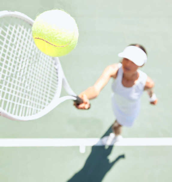 Mujer de tenis en pista de tenis con una pelota de tenis en el aire. Primer plano de una joven atleta golpeando la pelota con una raqueta de tenis para servir durante un partido o partido. Entrenamiento, diversión y deportes en acción. - Foto, imagen