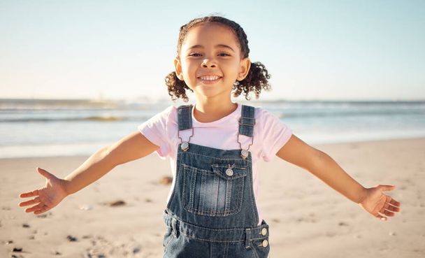 Beach, happy girl child and portrait on holiday, vacation or summer trip outdoors. Carefree, smile and happiness of fun kid in Mexico ocean, sea and sandy shore travel location, earth and blue sky - Photo, Image