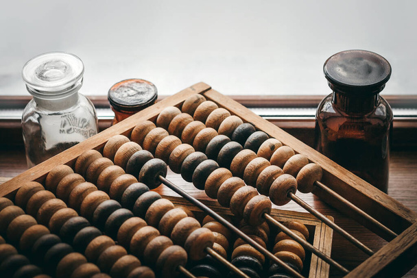 Old wooden abacus on a woden background in an old pharmacy with bottles and medicine - Фото, изображение