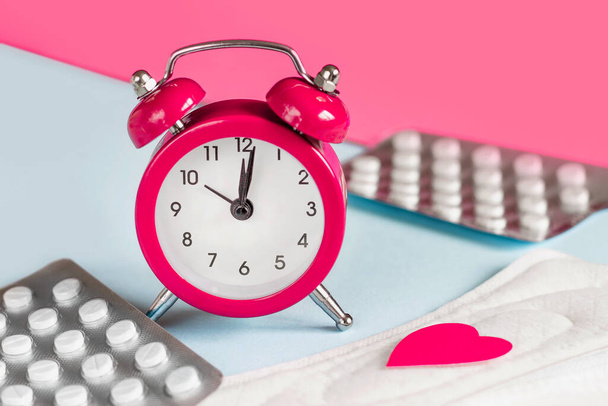 Menstrual pads, alarm clock, hormonal contraceptive pills. Menstruation period concept. Pain reliever for menstrual pain - Foto, afbeelding