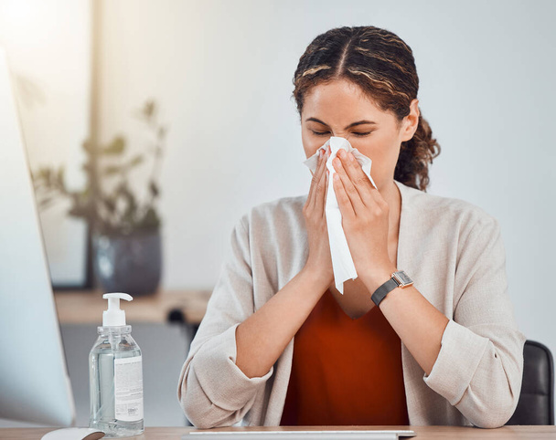 Covid, sick and woman blowing her nose with a tissue while working in her modern office during pandemic. Flu, cold or sinus allergy sneeze of girl from mexico sitting at her desk with health problems. - Photo, Image