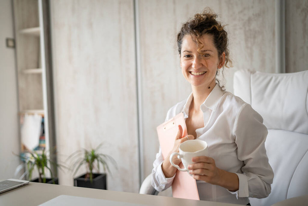 Jedna młoda kobieta kaukaska kobieta pracuje w biurze trzymając schowek i pijąc kawę nowoczesny biznes kobieta przedsiębiorca koncepcja - Zdjęcie, obraz
