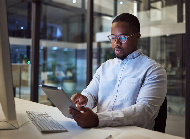 Black businessman, tablet and data analysis with computer in night office for digital marketing software, cybersecurity code or kpi. Thinking programmer, developer or website designer with technology. - Photo, Image