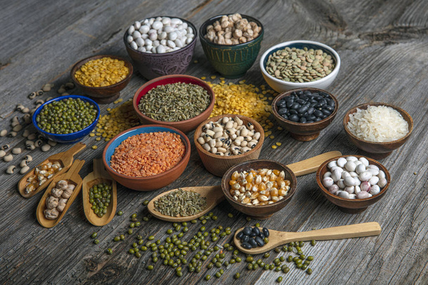Vegan protein source.Various assortment of legumes, lentils, chickpea and beans assortment in different bowls on wooden table. Top view. - Foto, immagini