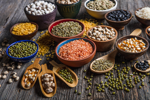 Vegan protein source.Various assortment of legumes, lentils, chickpea and beans assortment in different bowls on wooden table. Top view. - Fotó, kép