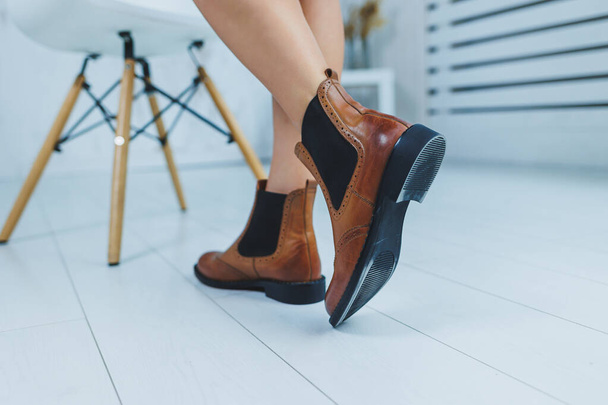 Közelkép a női lábakról barna bőr Chelsea csizmában. Új őszi kollekció női bőrcipőkből 2022 - Fotó, kép