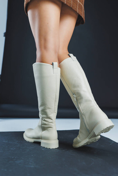 高級エレガントな白い女性の革フラットソールブーツ上の女性の足。冬の女性の革の靴のコレクション - 写真・画像