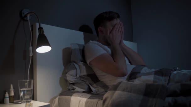 Theme is insomnia. Tired man suffers from poor sleep. Male in bed at night home rubbing eyes and yawning and cannot fall asleep. Sleeplessness concept. Problems with sleep, overwork. Sleep disorder.  - Footage, Video
