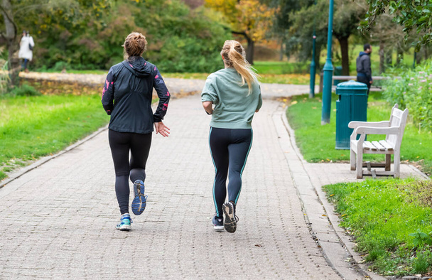 Jette, Région de Bruxelles-Capitale - Belgique - 11 05 2020 Deux jolies jeunes filles faisant du jogging dans un parc urbain - Photo, image