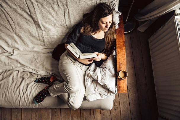 Vista panorámica de una mujer de 30 años en su sofá, leyendo un libro con un café, Bruselas - Foto, Imagen