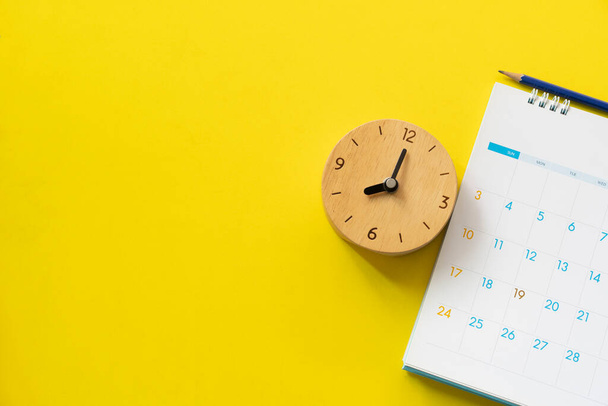 close up of calendar and clock on the yellow table background, planning for business meeting or travel planning concept - Foto, imagen