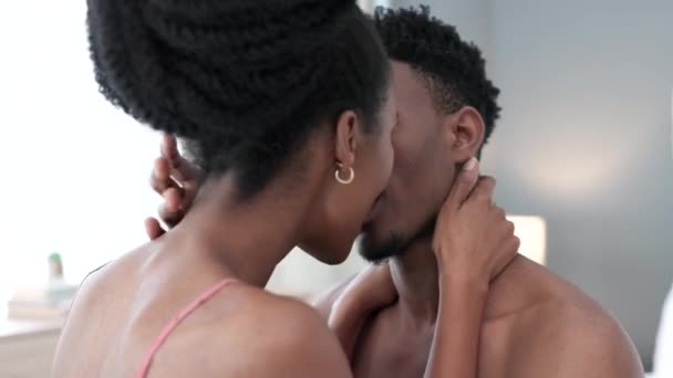 Zwart koppel zoent op bed in de slaapkamer thuis, een man en vrouw samen in relatie. Afro-Amerikaans meisje en jongen zoenen, sensueel en romantisch moment in de ochtend. Liefde, passie en intimiteit. - Video