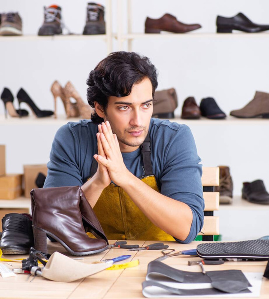 Jeune homme réparant des chaussures en atelier
 - Photo, image