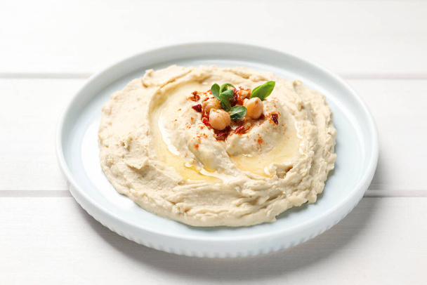 Tasty hummus with garnish on white wooden table - Foto, immagini