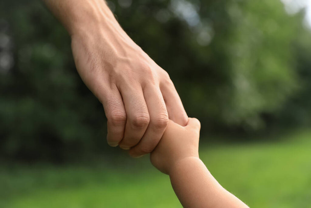 Daughter holding father's hand in park, closeup. Happy family - Φωτογραφία, εικόνα