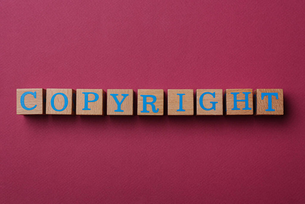 Wooden cubes with word Copyright on dark pink background, flat lay. Plagiarism concept - Foto, immagini
