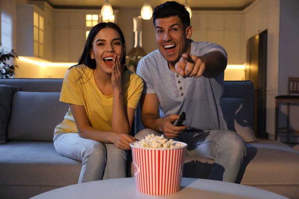 Couple watching movie with popcorn on sofa at night - Fotoğraf, Görsel