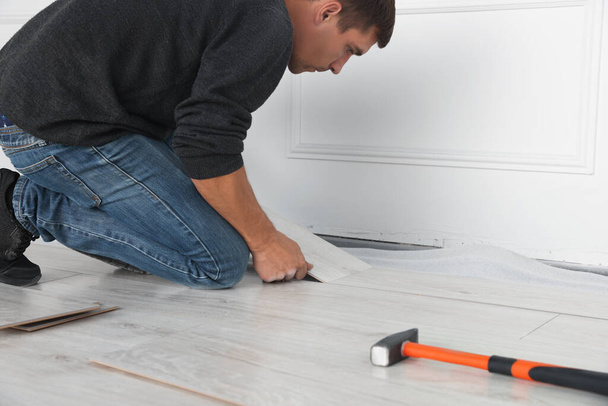 Worker installing new laminate flooring in room, closeup - Fotó, kép