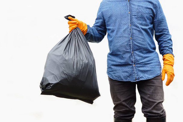Closeup  man holds black plastic bag that contains garbage inside. White background. Concept : Waste management. Environment problems. Daily chores. Throw away rubbish .  - Foto, imagen