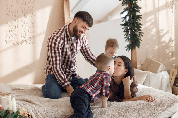 Mother, father and two their sons laying on a blanket. Boys with parents spending time together. Woman, man and two boys wearing plaid shirts. - 写真・画像
