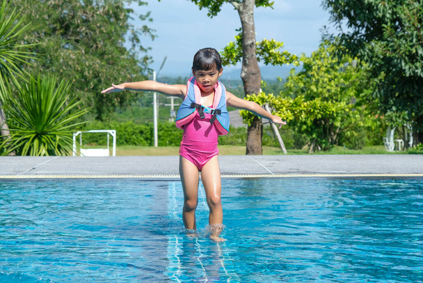 Happy little sisters play in outdoor swimming pool of tropical resort during family summer vacation. Kids learning to swim. Healthy Summer Activities for Kids. - Fotoğraf, Görsel