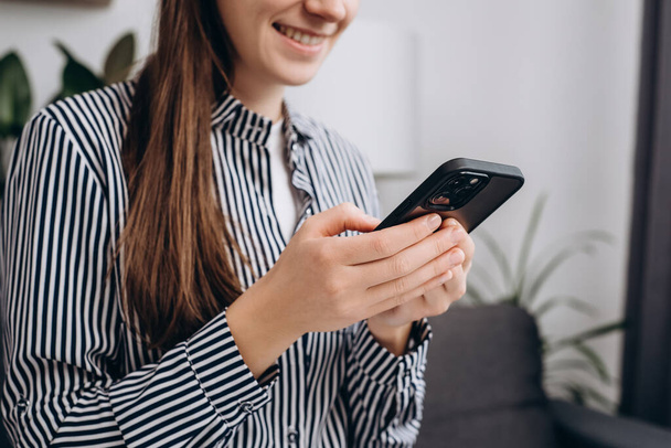 Close up of happy smiling young caucasian female using smartphone at home or smart office, positive girl using cell phone and texting. Technology, startup, new business and communication concept - Foto, immagini