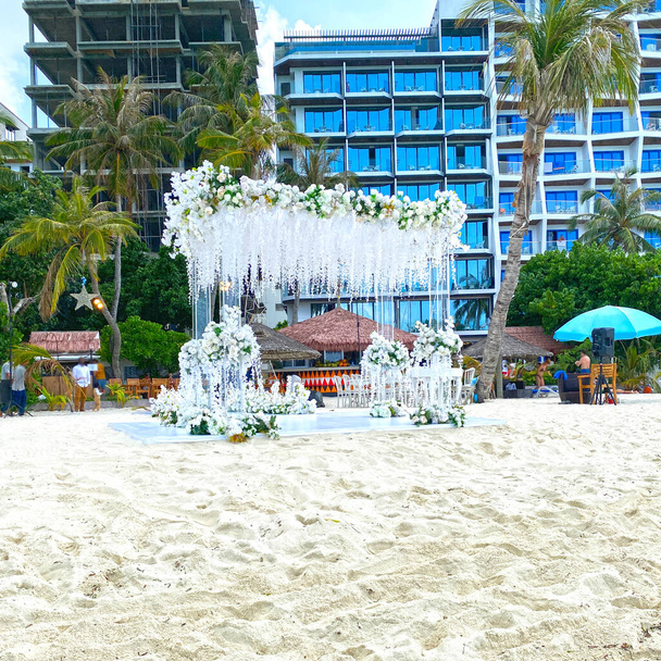 結婚式の準備、ホテルの近くのモルディブの白い砂の上のビーチで美しい白い装飾が施された公式儀式の場所 - 写真・画像