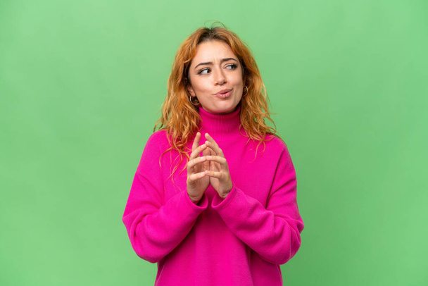 Young caucasian woman isolated on green screen chroma key background scheming something - Photo, Image