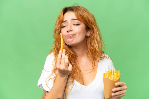 Young caucasian woman holding fried chips isolated on green screen chroma key background - Photo, image