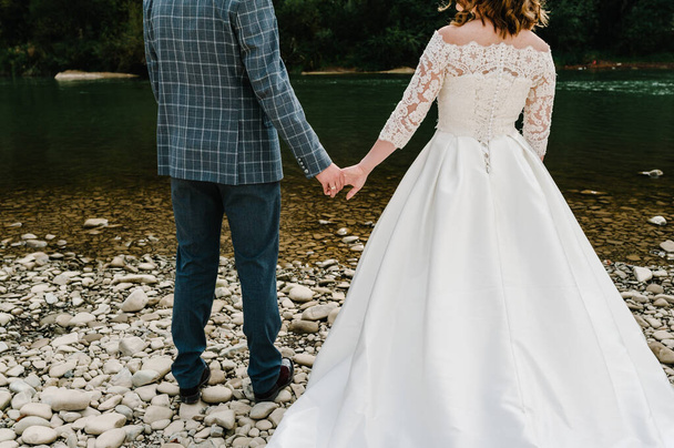 The bride and groom holding hands. Engagement.  Newlyweds of the outdoors. Close up. Back view. - Фото, изображение