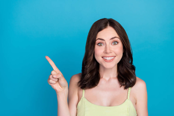 Portrait of pretty positive lady beaming smile direct finger empty space isolated on blue color background. - Foto, Imagem