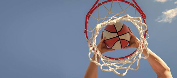 basketbalista hodí míč do koše na pozadí oblohy, na cíl. Horizontální design plakátu. Záhlaví nápisu na webu, místo pro kopírování - Fotografie, Obrázek