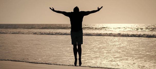Мужчина прыгает, плакат с копировальным пространством. здоровый мужчина силуэт поднял руки на пляже. энергичное лето. почувствовать свободу - Фото, изображение