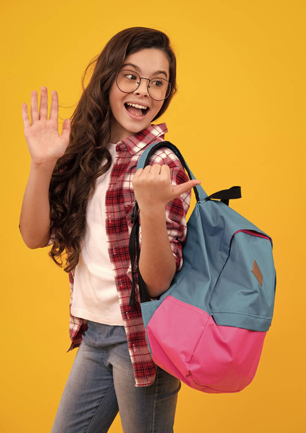 Koulupukuinen koulutyttö koululaukun kanssa. Koululainen teini pidä reppu keltainen eristetty tausta. Onnellinen teini-ikäinen, positiivinen ja hymyilevä tunteita teini tyttö - Valokuva, kuva
