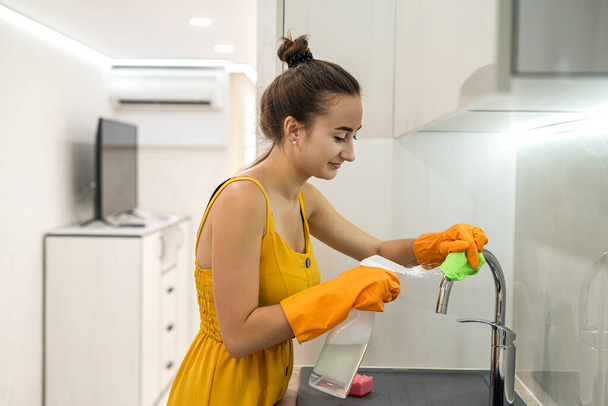 mujer en trapo amarillo limpieza de su fregadero de cocina, limpieza - Foto, Imagen