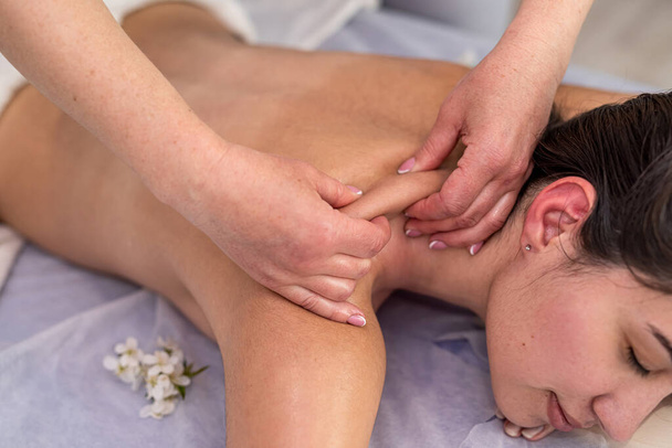 женщина лежит на кровати и закрытый глаз, получая расслабляющий массаж спины в спа-салоне. Концепция косметики - Фото, изображение
