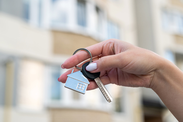 Holding house keys and a house shaped keychain to buy a new house. realtor with keys - Photo, Image