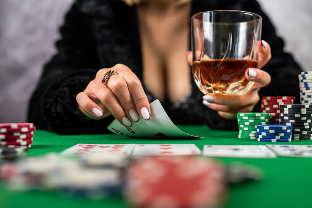 Elinde poker kartları ve fişleri olan seksi bir kadın masada poker oynuyor. Poker, yakalı bir elbise giymiş kumarbaz bir kadın. - Fotoğraf, Görsel