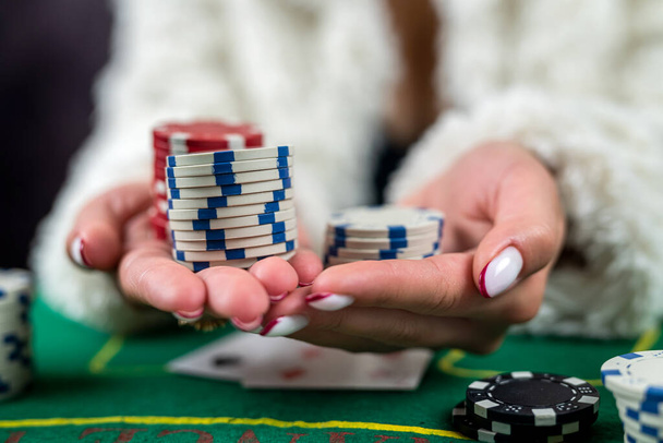 cropped image of girl in evening dress playing poker and taking chips at casino table. poker game focusing on cards - Photo, Image