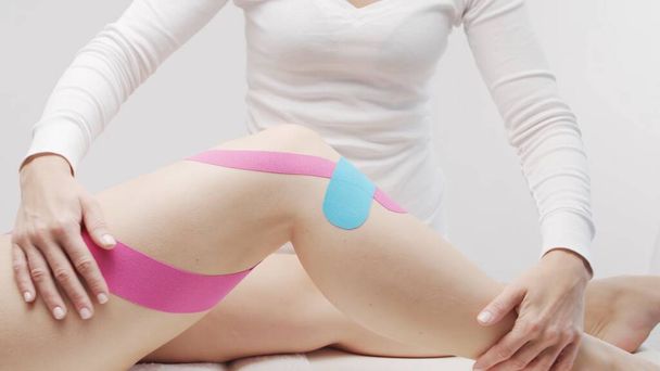 Therapist is applying tape to beautiful female body. Physiotherapy, kinesiology and recovery treatment. - Zdjęcie, obraz