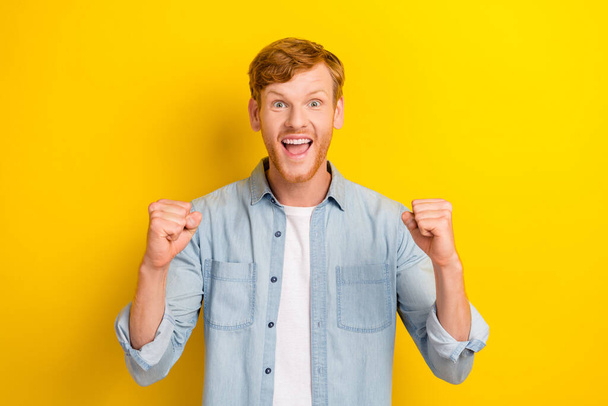 Photo portrait of handsome young man watch sport match raise fists support dressed trendy denim look isolated on yellow color background. - Foto, Bild