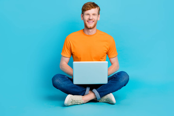 Full length photo of positive charming man wear orange t-shirt communicating modern device isolated teal color background. - Φωτογραφία, εικόνα