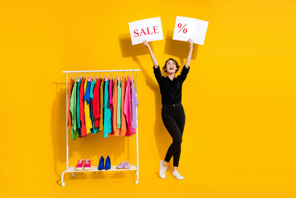 Photo of impressed excited girl dressed formal shirt rising discount percent empty space copyspace isolated yellow color background. - Valokuva, kuva