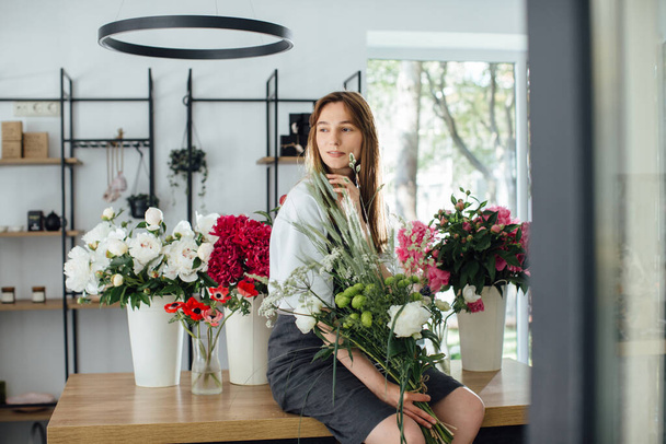 Florista mulher no espaço de trabalho da loja de flores. - foto stock - Foto, Imagem